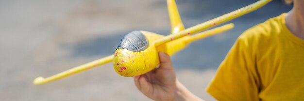 Fröhliches Kind, das mit Spielzeugflugzeug vor altem Start- und Landebahnhintergrund spielt und mit Kinderkonzeptbanner reist