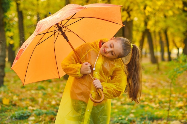 Fröhliches Kind, das Regentropfen im Herbstpark fängt