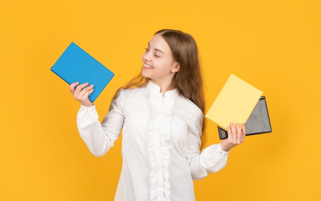 Fröhliches kind, das schulbuch auf gelbem hintergrund zeigt, zurück zur schule