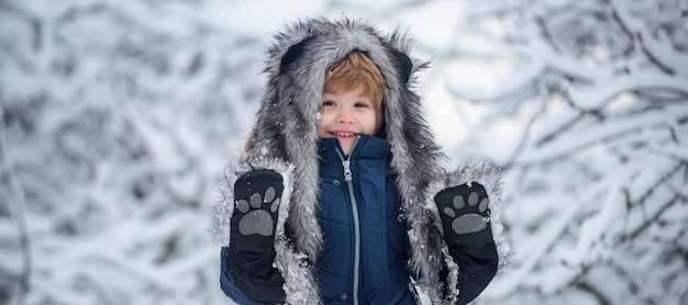 Fröhliches Kind, das sich im Winterpark amüsiert Süßes Kind im Winterpark Bäume mit Schnee bedeckt und gut gekleidet