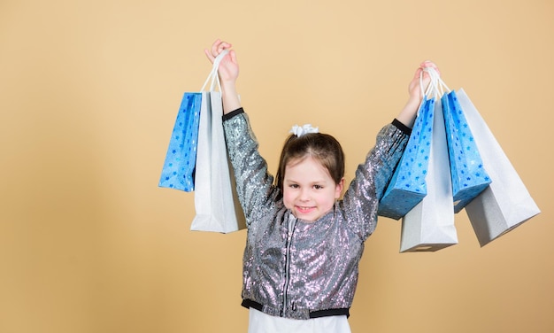 Foto fröhliches kind kleines mädchen mit geschenken einzelhandelsgeschäft urlaubskauf sparen mode und stil kunde mit paket einkaufszentrum verkäufe und rabatte kleines mädchen mit einkaufstaschen fangen sie den moment