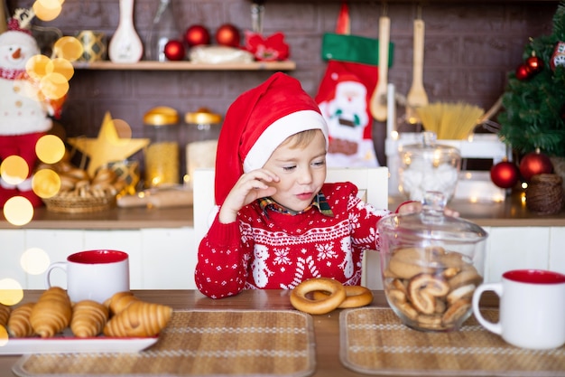 Fröhliches Kind Kleinkind feiert Weihnachten in der Küche zu Hause Frohe Weihnachten und ein glückliches neues Jahr