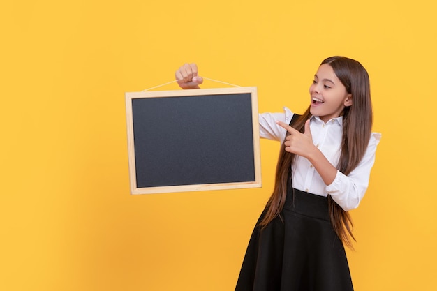 Fröhliches Kind mit einheitlichem Zeigefinger auf der Schultafel für Werbung im Kopierbereich