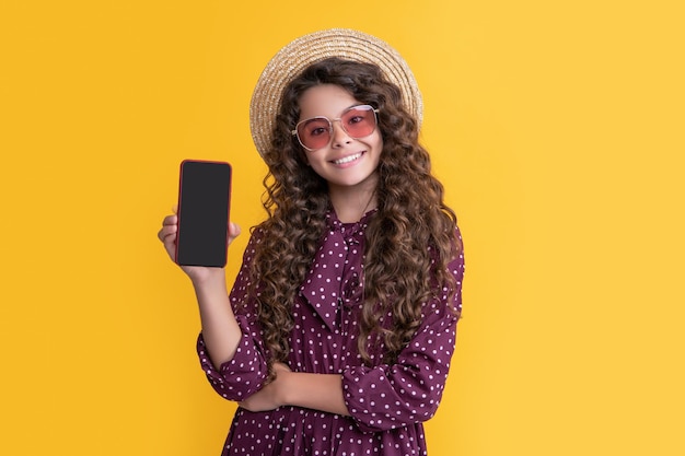 Fröhliches Kind mit lockigem Haar, das den Bildschirm des Smartphones mit Kopierraum präsentiert