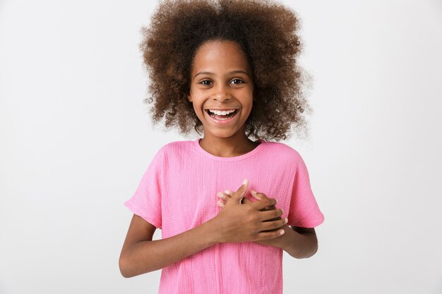 Fröhliches kleines afrikanisches Mädchen mit rosa Bluse steht isoliert über weißer Wand und zeigt Herzgeste