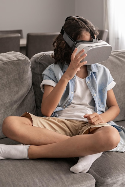 Fröhliches kleines Jungenkind mit Virtual-Reality-Headset vr-Brille, das zu Hause gestikuliert und Spaß hat