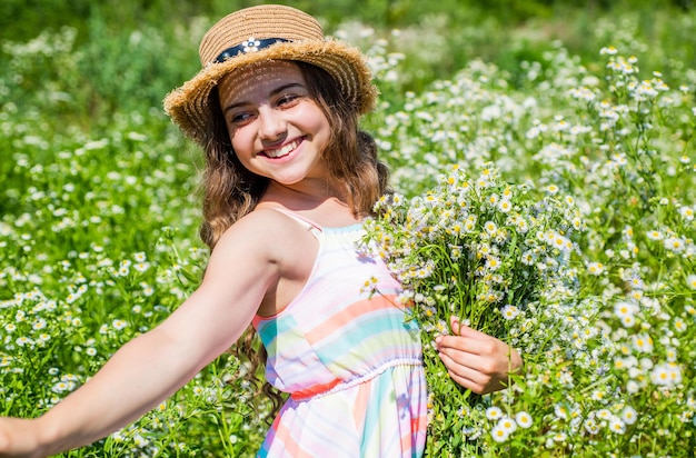 Fröhliches kleines Mädchen, das an einem sonnigen Tag Blumen und Kräuter sammelt