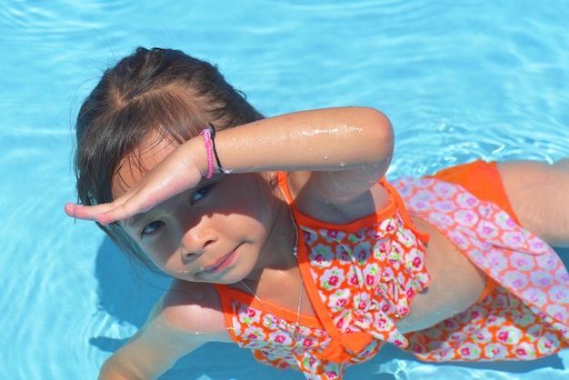 Fröhliches kleines Mädchen im Schwimmbad an einem heißen Sommertag. Kinder lernen schwimmen. Kinder-Wasserspielzeug. Kinder