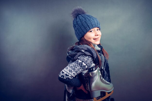 Fröhliches kleines Mädchen in warmem Pullover und Hut mit Eiskunstlauf.