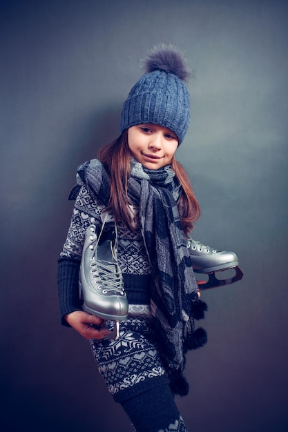 Fröhliches kleines Mädchen in warmem Pullover und Hut mit Eiskunstlauf.