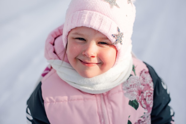 Fröhliches kleines Mädchenporträt des Kindes im Winter warme rosa Kleidung, die sich auf einem Spaziergang auf frostigem M...