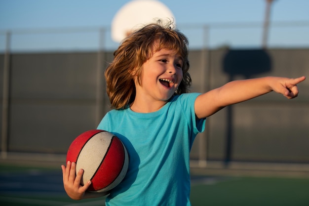 Fröhliches lächelndes Kind, das Basketball spielt und Gestenaktivität und Sport für Kinder zeigt