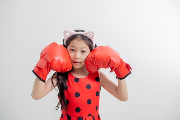 Fröhliches lustiges kleines Mädchen mit roten Boxhandschuhen isoliert
