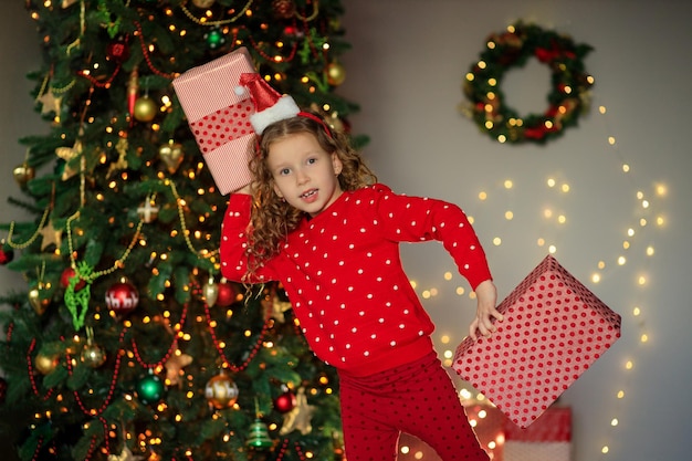 Foto fröhliches lustiges kleines mädchenbaby mit neujahrsgeschenken am baum