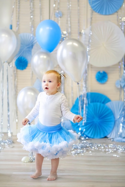 Fröhliches Mädchen, das an ihrem Geburtstag auf dem Papst im festlichen Kinderzimmer sitzt