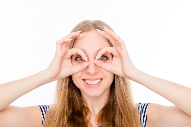 Foto fröhliches mädchen, das finger nahe augen wie brille hält