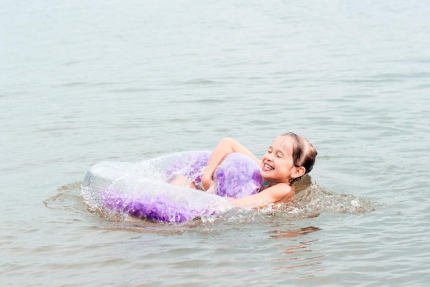 Fröhliches Mädchen, das sich an einem aufblasbaren Ring im Fluss festhält Lokaler Tourismus Sommerurlaub