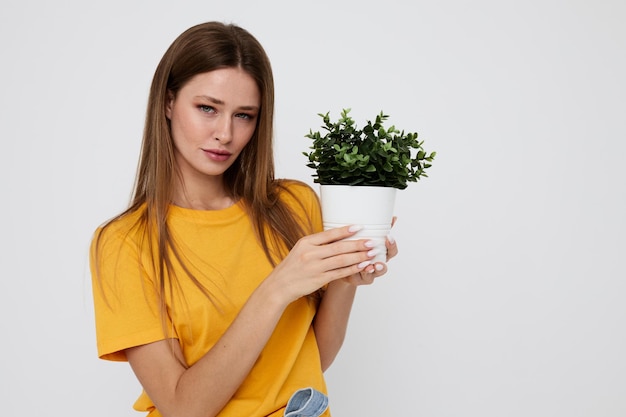 Fröhliches Mädchen in einer gelben T-Shirt-Blume in einer Topfaufstellung