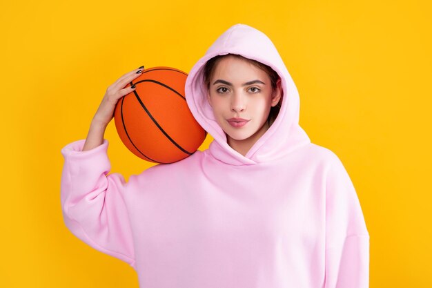 Fröhliches Mädchen mit Basketballball auf gelbem Hintergrund