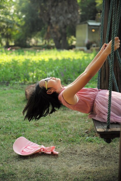 Foto fröhliches mädchen sitzt auf einer schaukel im park