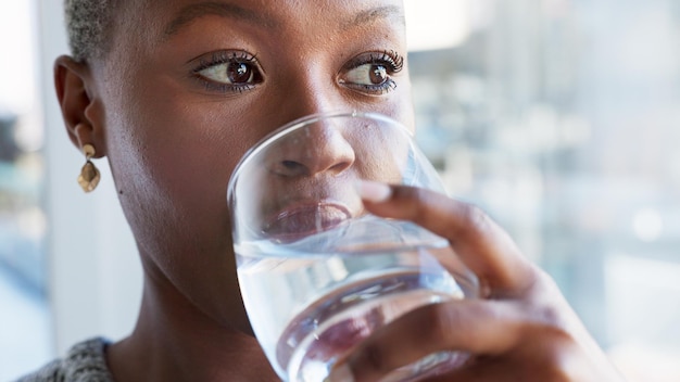 Foto fröhliches mädchen trinkt wasser, während es sich im restaurant, café oder geschäft entspannt, und genießt den ruhigen sommertag, die ruhe allein für wellness, stressabbau-lächeln und das gesicht einer schwarzen frau, die aus dem glasfenster des ladens schaut