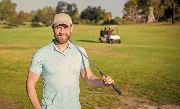 Fröhliches Mannporträt, das Golfspiel auf grünem Grasgolf spielt