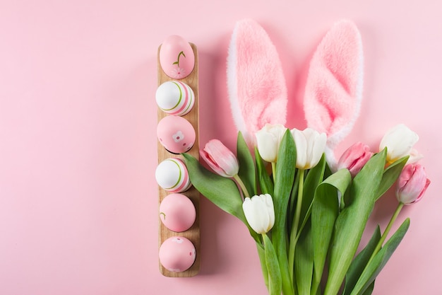 Fröhliches Osterferien-Hintergrundkonzept Flach lag mit Tulpen, Blumen, Hasenohren und Ostereiern