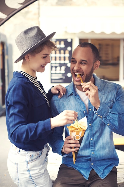 Fröhliches Paar, das Essen zum Mitnehmen probiert?