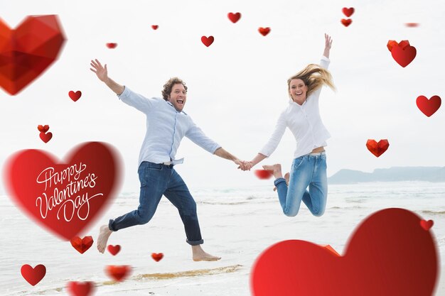 Fröhliches Paar, das Händchen hält und am Strand gegen süße Valentinsbotschaft springt