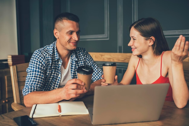 Fröhliches Paar, das mit Laptop arbeitet und redet