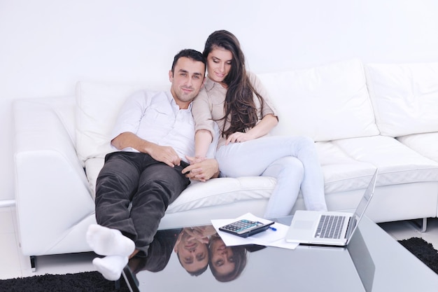 Fröhliches Paar entspannen und arbeiten am Laptop im modernen Wohnzimmer im Innenbereich