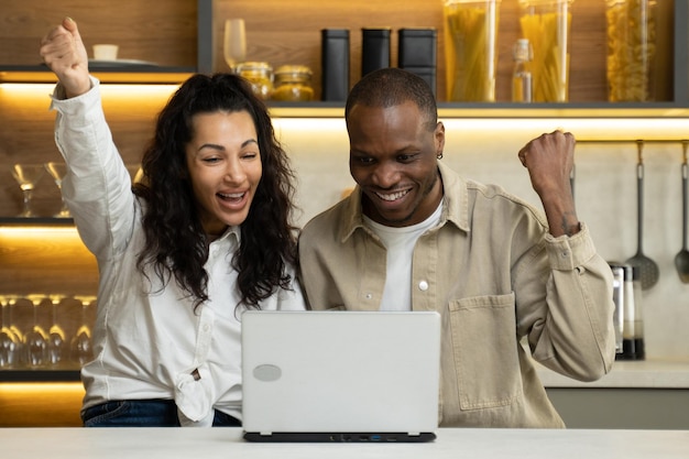 Fröhliches paar freut sich über einen lottogewinn im laptop zu hause