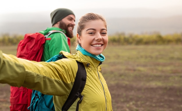 Fröhliches Paar mit Rucksäcken, die in der Herbstnatur wandern