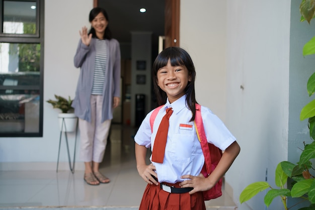 Fröhliches Porträt des schönen asiatischen Grundschülers, der morgens zur Schule geht