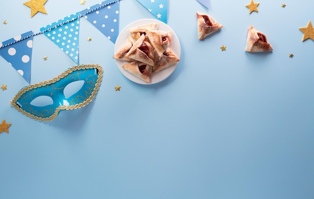 Fröhliches Purim-Karnevalsdekorationskonzept aus Maske und funkelndem Stern und Hamantaschen-Keksen auf pastellfarbenem Hintergrund Fröhliches Purim in hebräischen jüdischen Feiertagen feiern