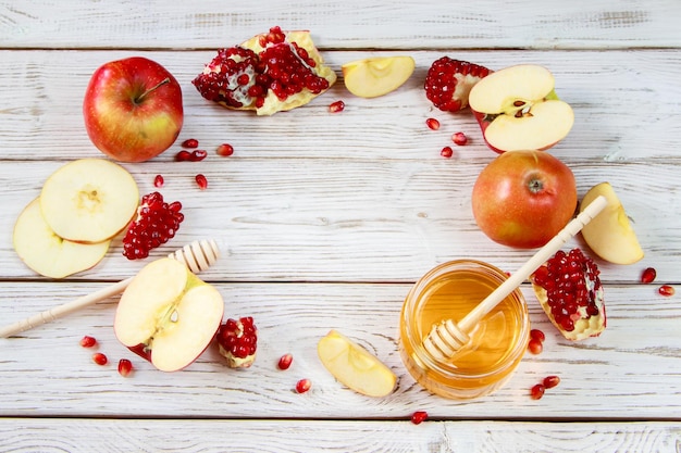 Fröhliches Rosh Hashanah Traditionelle Symbole der jüdischen Neujahrsfeier Äpfel Granatäpfel und Honig auf weißem Holzhintergrund