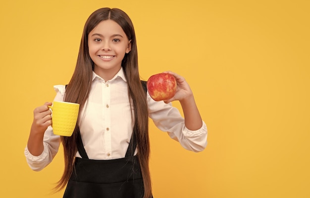 Fröhliches Schulkind in Uniform hält Apfel und Wasserflasche mit Wasser