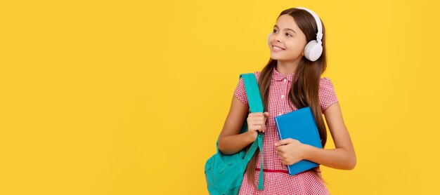 Fröhliches Schulkind mit Kopfhörern trägt Rucksack und Arbeitsbuch ebook Banner der Schülerin Schulkind-Schülerporträt mit Kopierbereich