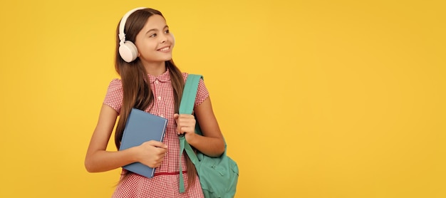 Fröhliches Schulkind mit Kopfhörern trägt Rucksack und Arbeitsbuch ebook Banner der Schülerin Schulkind-Schülerporträt mit Kopierbereich