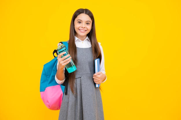 Fröhliches Schulmädchen mit Büchern trinkt Wasserflasche am Schultag Zurück zum Lifestyle-Konzept der Schule