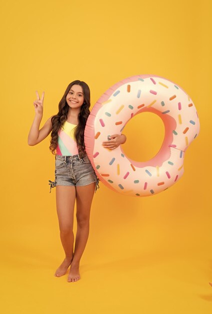 Fröhliches Strandkind mit aufblasbarem Donut-Ring für Poolparty-Spaß im Sommerurlaub Sommer