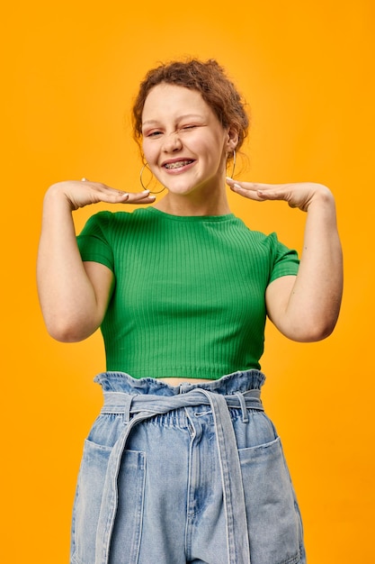 Fröhliches süßes Mädchen mit Ohrringen grüne T-Shirts gelber Hintergrund