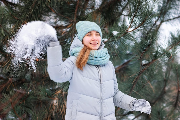 Fröhliches Teenager-Mädchen, das Spaß beim Spielen mit Schneebällen hat und bereit ist, den Schneeball zu werfen.