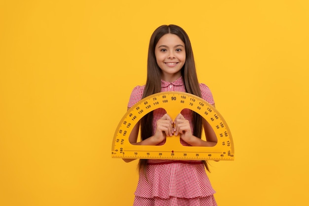 Fröhliches Teenager-Mädchen studiert Mathematik in der Schule und hält Winkelmesser-Linealgeometrie