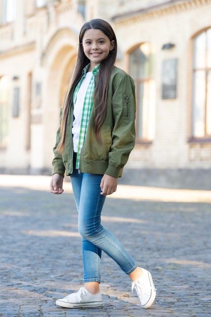 Fröhliches Teenie-Mädchen-Model posiert im lässigen, trendigen Stil im Freien