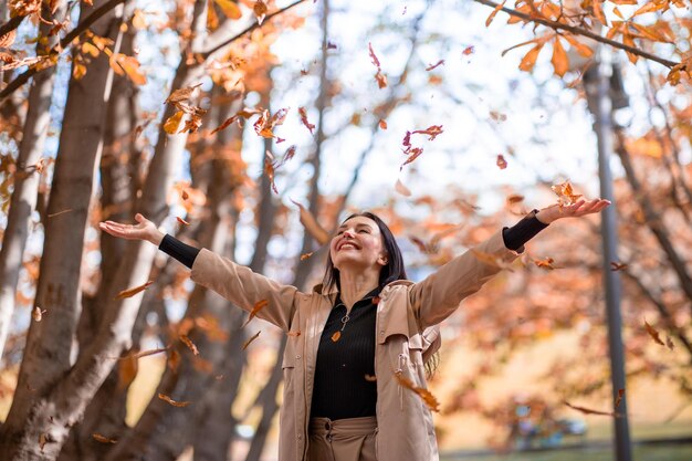 Fröhliches und stilvolles Frauenporträt in der Herbstsaison posiert sie mit gelbem Blatt