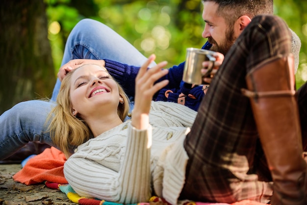 Fröhliches verliebtes Paar entspannen im Herbstwald bei Tee oder Kaffee Camping und Wandern Glückliche Frau und bärtiger Mann trinken Glühwein Liebestermin und Romantik Familienpicknick Valentinstag