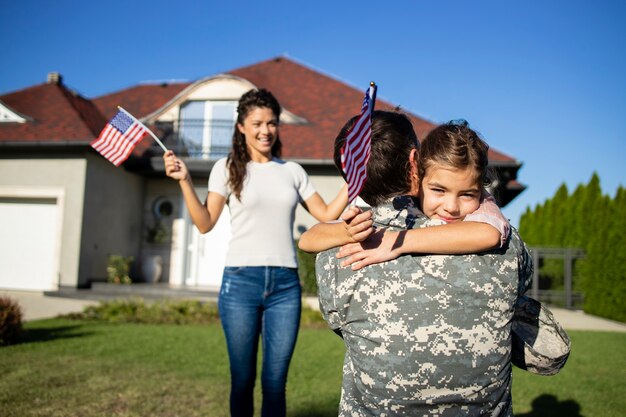 Fröhliches Wiedersehen des Soldaten mit seiner Familie im Freien vor ihrem Haus.