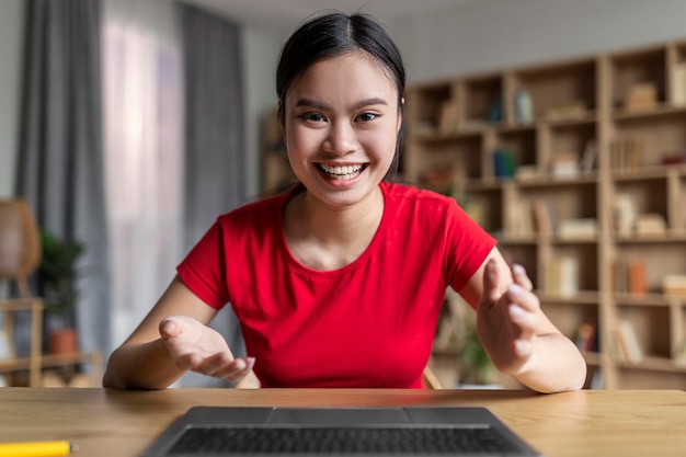 Foto froh, aufgeregt, junge asiatische studentin freut sich und schaut auf computerbildschirm hat online-chat im innenraum