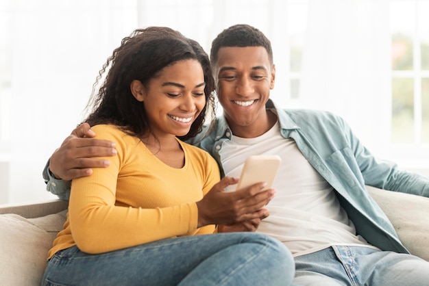 Froh junger afroamerikanischer Mann und Frau schauen sich das Telefon an und haben Videoanrufe Video ansehen